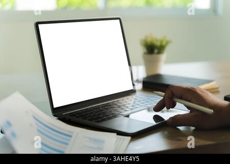 businessman is sitting at a desk in a modern office with a laptop. The laptop screen is blank Stock Photo