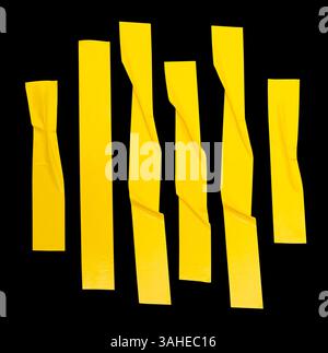 Top view set of wrinkled or crumpled yellow adhesive vinyl tape or cloth tape in stripes shape in vertical is isolated on black background. Stock Photo