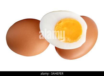 Front view of raw brown chicken eggs and cooked or boiled chicken egg with egg yolk in half in stack is isolated on white background Stock Photo