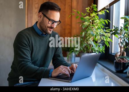 Success man typing on laptop, communicating online distantly working or studying on computer at home Stock Photo