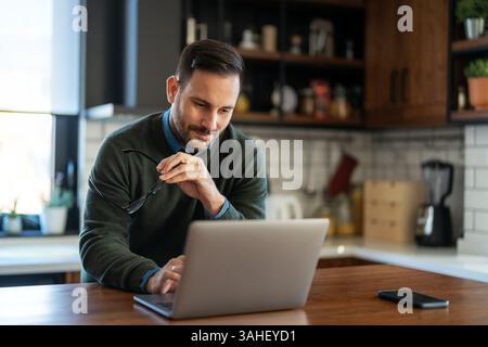 Satisfied man using laptop computer for electronic banking, making reservation, online shopping Stock Photo