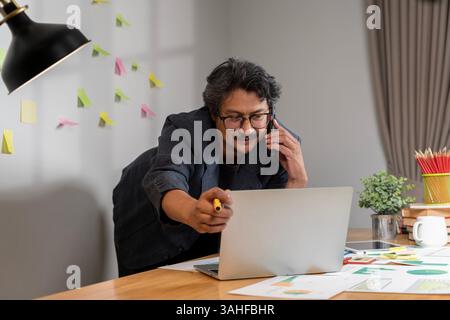Cheerful young business professional working intently in modern office environment. A mid adult Caucasian man in business attire works intently on a l Stock Photo