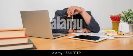 Young worker fell asleep on the workplace in the office on the keyboard. Sleep deprivation and overtime overload working concept. Keyboard imprinted o Stock Photo