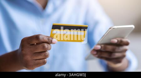 Online Payment. Unrecognizable black female using smartphone and credit card in office Stock Photo