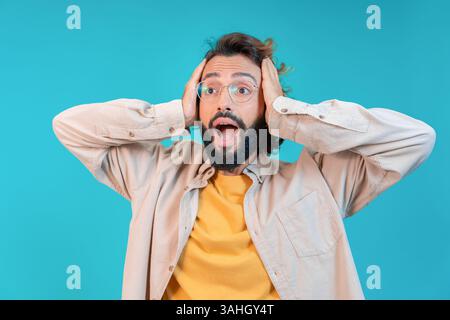Surprised Man Expressing Shock and Disbelief with His Hands Raised on His Head in Awe Stock Photo