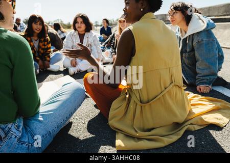 A diverse group of individuals sit outdoors, participating in a peaceful demonstration, and engaging in discussions around a common cause. Stock Photo