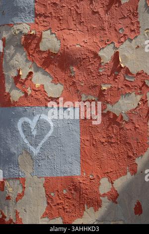 Old wall with peeled off facade in a red color. Grey details and a white painted heart. Las Palmas, Gran Canaria, Canary Islands, Spain. Stock Photo
