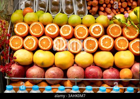Freshly sliced oranges and an array of fruits displayed on a market stand. Stock Photo