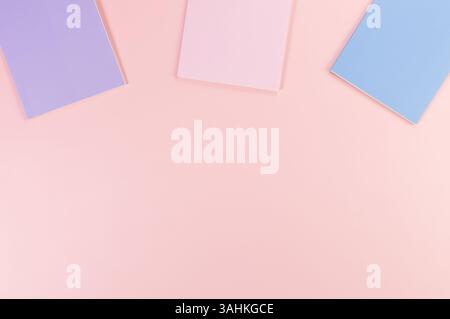 Top view of pink, purple and blue notebooks on pink background. School, office wallpaper. Flat lay, copy space. Stock Photo