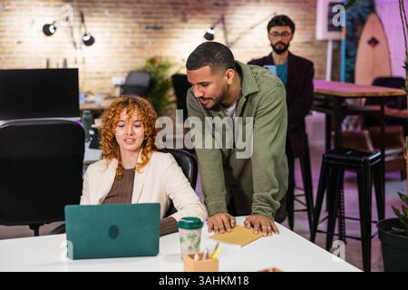 Multi ethnic team collaborating on laptop in modern office Stock Photo