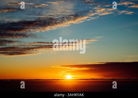 A breathtaking sunset over the ocean with vibrant orange and blue hues and scattered clouds. Monterey, CA, USA Stock Photo