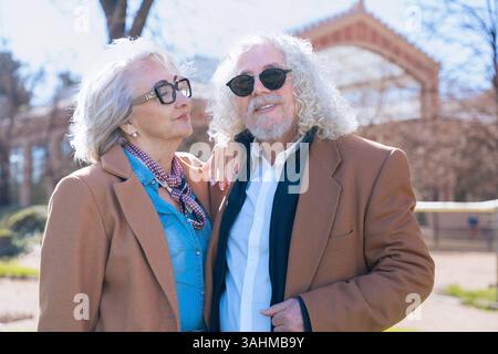 Caucasian senior couple smiling and posing outdoors together in sunny urban park Stock Photo