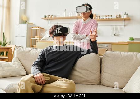 A young asian couple engages with virtual reality headsets, sharing an immersive experience at home. Stock Photo