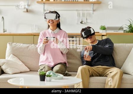 A couple enjoys virtual reality gaming together on the sofa, relaxing and having fun. Stock Photo