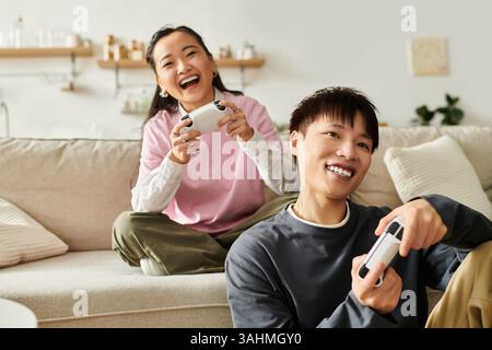 Young couple enjoys an entertaining gaming session in their cozy living room filled with laughter. Stock Photo