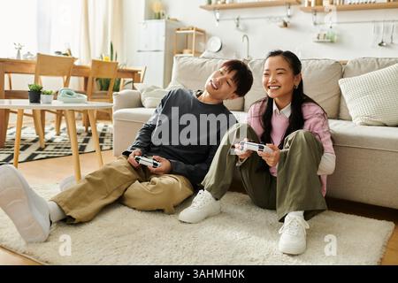A happy couple plays video games on the floor at home, enjoying a cozy moment together. Stock Photo