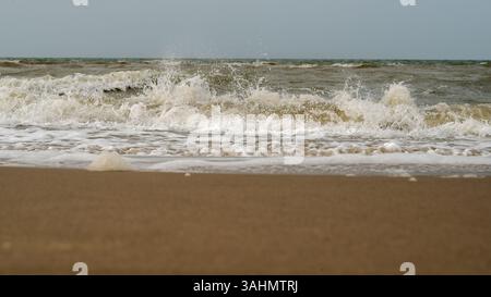 A beautiful and serene view of gentle ocean waves crashing harmoniously onto a sandy beach during dusk hours Stock Photo