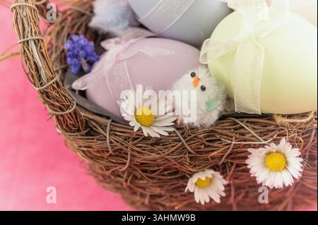 A beautifully arranged festive Easter basket brimming with pastelcolored eggs and an endearing fluffy chick Stock Photo