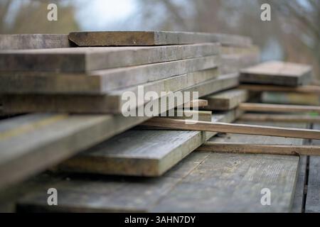 Stacked wooden planks prepared for carpentry or construction work, scaffolding boards, and outdoor setting. Timber drying for building use Stock Photo
