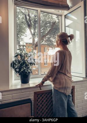 A woman looks out the window on a sunny summer day in Odessa Stock Photo