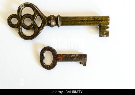 Large and Small Antique Brass Skeleton Keys on White Background, shown at a side view macro closeup Stock Photo