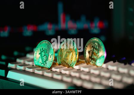 Bitcoin coins on computer keyboard with trading chart in background Stock Photo