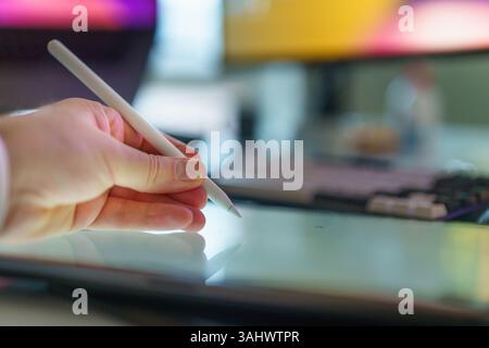 Designer using stylus pen on digital tablet in modern workspace Stock Photo