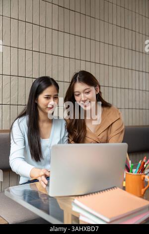 Study Session and Collaboration. Two university students engaged in a collaborative study session at a cafe. Stock Photo