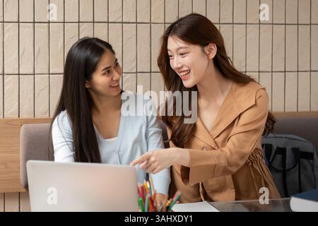 Study Partnership and Learning Environment. Two university students collaborating on a project in a modern cafe setting. Stock Photo