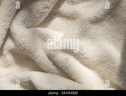 Beige soft eco-fur textile and textured pleats in sunlight, beautiful shadows. Stock Photo