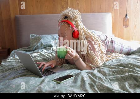 Woman using laptop on bed Stock Photo