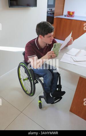 Man in wheelchair doing paperwork at home Stock Photo