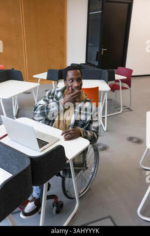 Man in wheelchair at desk in office Stock Photo