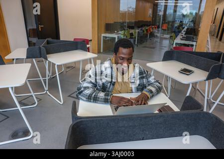Man in wheelchair using laptop in office Stock Photo
