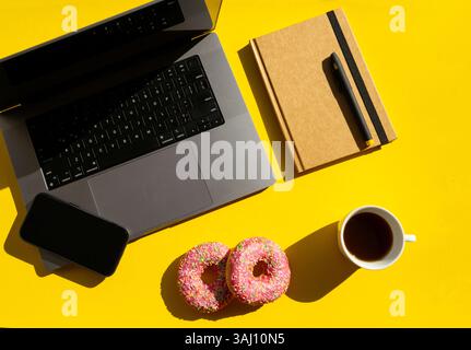 laptop, smartphone, notepad and coffee with donuts flatlay Stock Photo