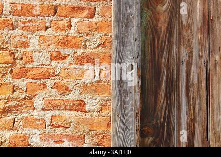 Orange brick wall with vertical wooden panel detail, rustic facade from a vintage countryside building. Stock Photo