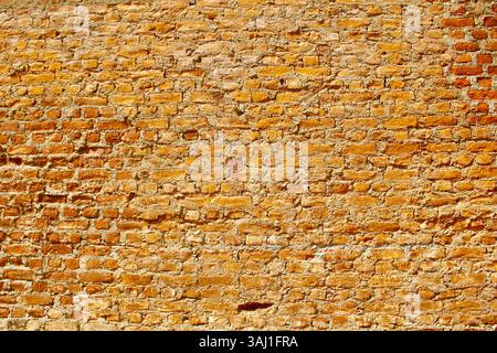 Bright orange and yellow brick wall, vibrant rustic texture suitable for backgrounds and architectural design elements. Stock Photo