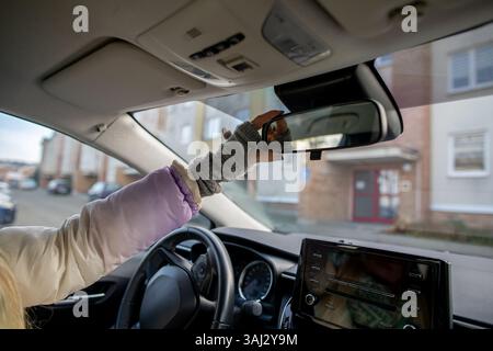 Adjusting the rearview mirror in a car is essential for safety and visibility while driving Stock Photo