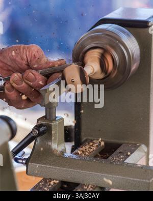 Close-up of old carpenter working woodwork. Piece of wood is worked by hand. A traditional treatment of round wood shapes. Stock Photo