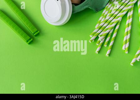Eco-friendly disposable tableware and kitchenware on a green background. Stock Photo