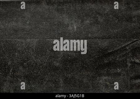 Background of black old leather close-up, the leather is grainy dusty and dirty Stock Photo