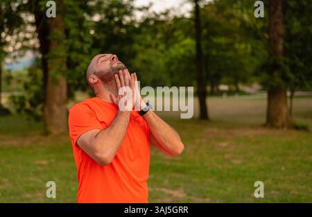 A sporty man is doing stretching exercises before running or workout outdoor in the summer park active healthy lifestyle.  Stock Photo