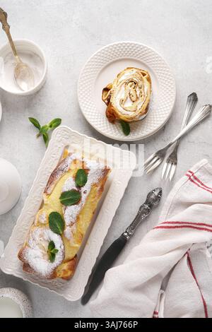 Finnish pancake in the roll cake with cream on white plate ant cut piece near on light background, top view Stock Photo