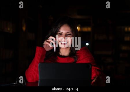 Scene of a pretty young business woman working late at night to meet an urgent deadline. Stock Photo