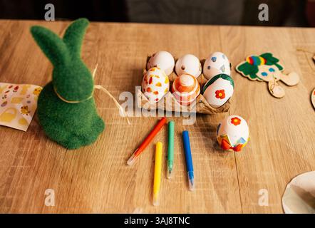 Colorful Easter egg decorating activity with crafts on a wooden table during spring festivities Stock Photo
