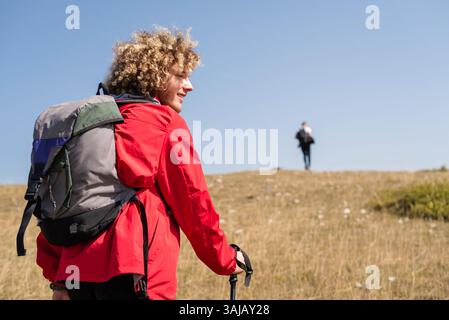 A young happy male traveler enjoys team hiking or trekking trail mountain, active lifestyle. Stock Photo