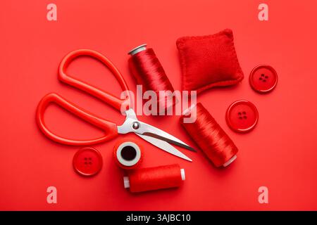 Different sewing supplies on red background, flat lay Stock Photo
