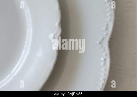Edge detail of white China plates on a white tablecloth Stock Photo