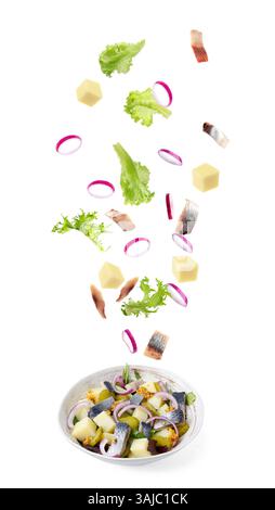 Delicious herring salad isolated on white. Fresh ingredients flying over bowl Stock Photo