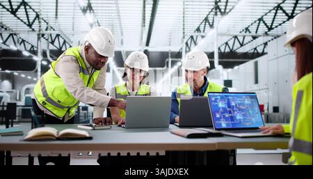 Skilled Woman Oversees Diverse Team Working At Electronic Equipment Factory. Stock Photo